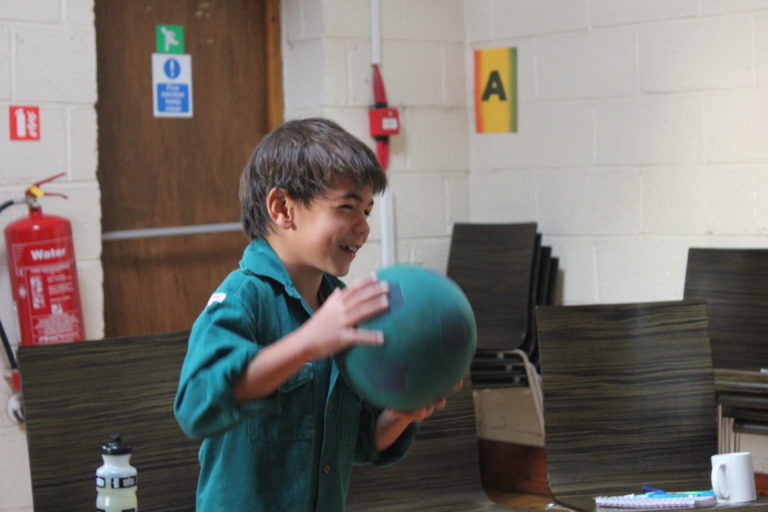 An Elfin in a woodcraft folk shirt, throwing a ball