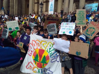 Large group of children with a homepainted woodcraft folk banner at a climate demonstration