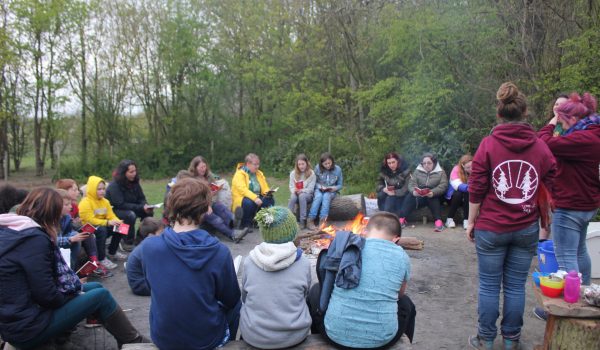 children and adults sitting around a campfire