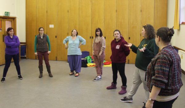 7 adults standing in a circle talking at a Woodcraft Folk new groups training session