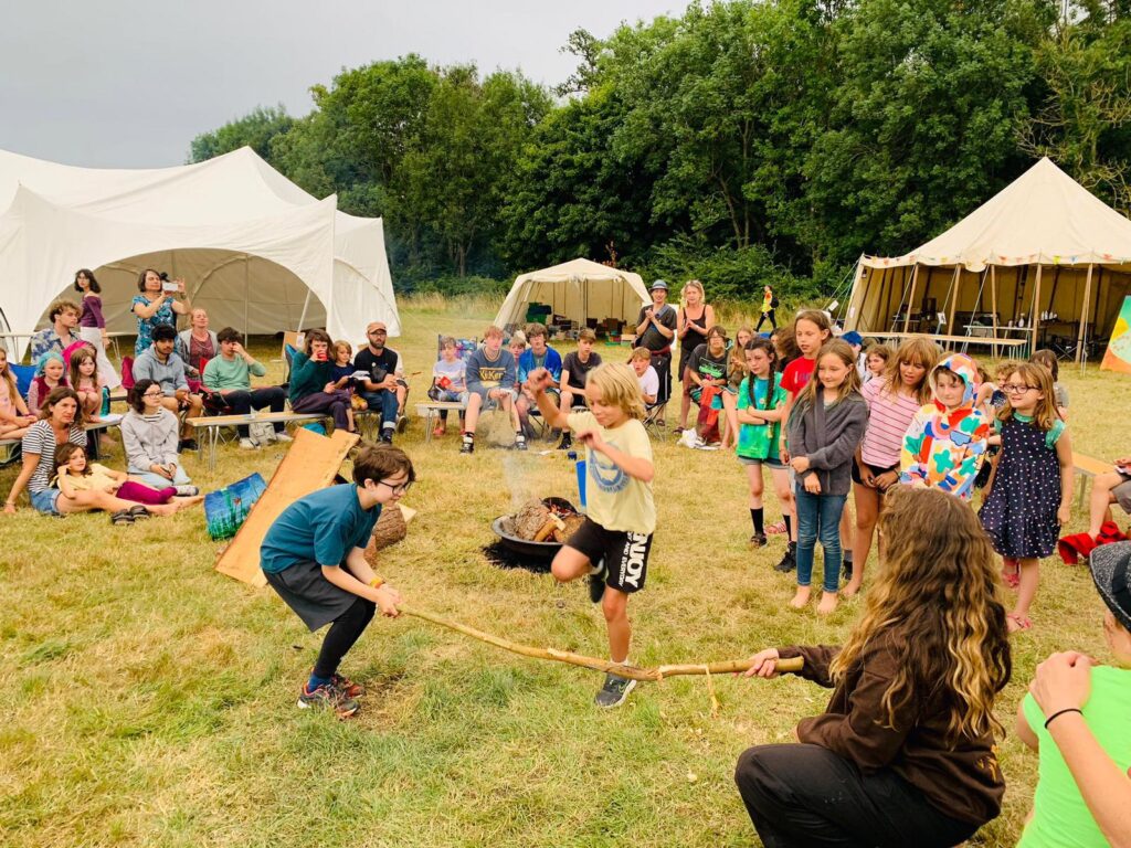 A group of children jump over a stick held by other children