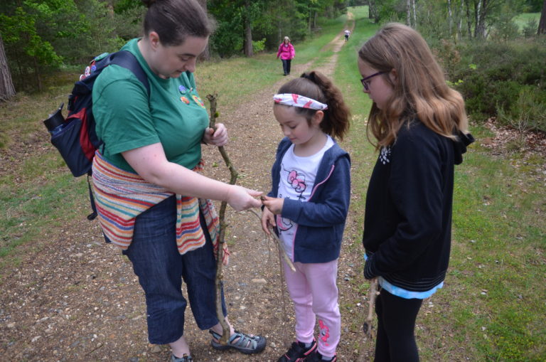 a volunteer in a woodcraft folk t shirt helping a child on a walk