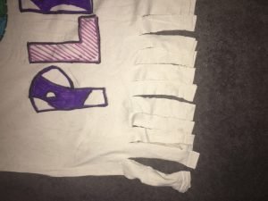 the t-shirt is decorated and the bottom of the shirt is cut into little lines to create the knots 