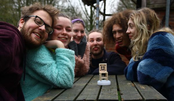 6 DFs sitting around a miniature chair with a woodcraft symbol carved into it