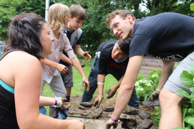 group of volunteers and children building a wall