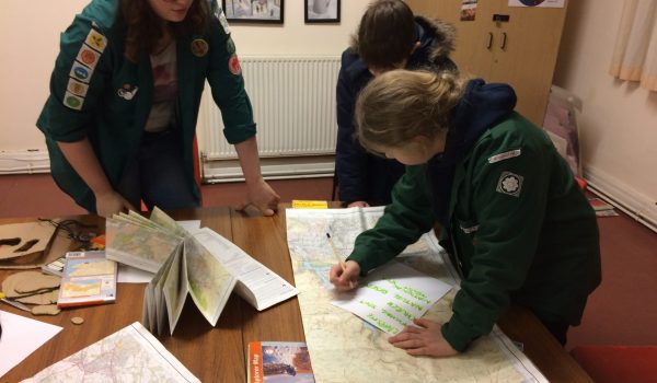 A volunteer helping two venturers with a map