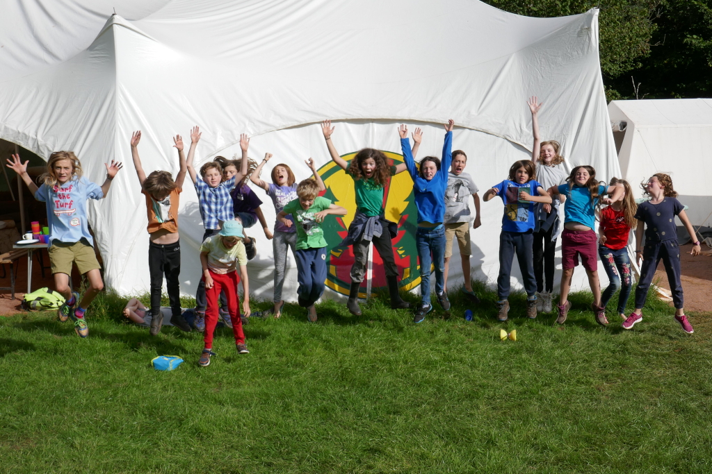 15 children jumping in front pf the marquee at Biblins campsite