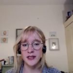 Young woman sitting at zoom screen in headphones