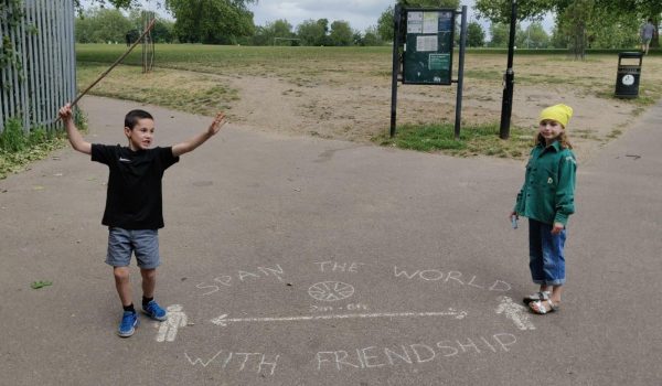 two children standing either side of a 2m distance sign