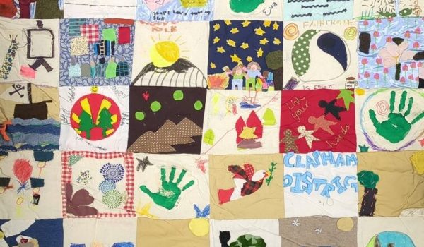 A large textile quilt made by Woodcraft Folk Elfin Groups. You can see the names of some groups on the quilt, Brightlingsea Elfins, and Clapham District.