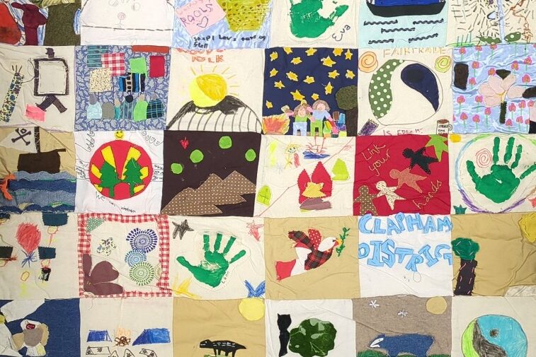 A large textile quilt made by Woodcraft Folk Elfin Groups. You can see the names of some groups on the quilt, Brightlingsea Elfins, and Clapham District.